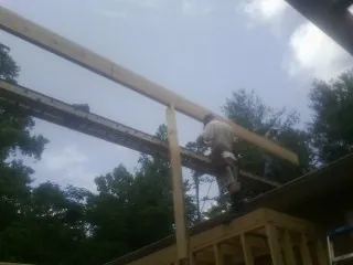 Carpenter setting a ridge beam over a new addition frame — Ice Dam Removal by Roofing Brothers in Portland